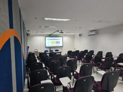 Sala Nazian, vista da parte da frente da sala, mostrando a tela de projeção, mesa com três cadeiras